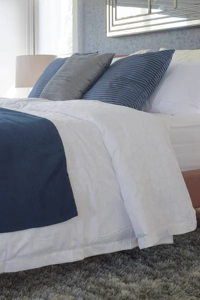 Сині і сірі подушки, встановлені на ліжку з зеленим килимком — стокове фото