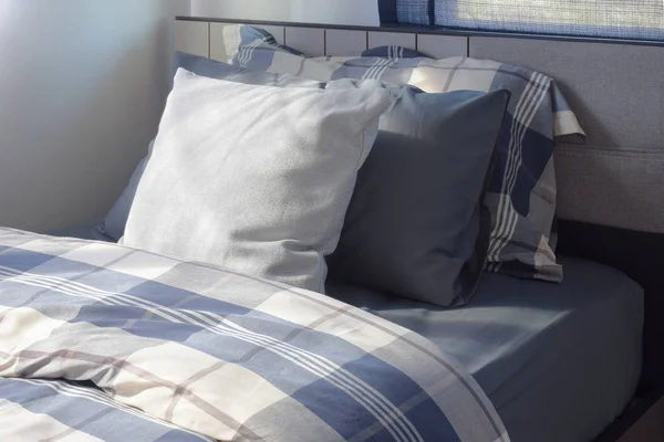 White and deep blue pillow on bed checked pattern bedding in modern interior bedroom