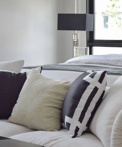 Черно-белая графическая подушка на белом диване рядом с кроватью — стоковое фото