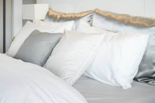 Подушки серого цвета, установленные на кровати с атласными постельными принадлежностями — стоковое фото