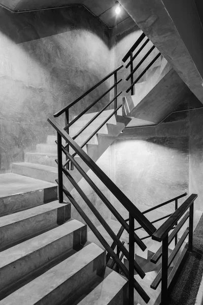 Empty modern rough concrete stairway with black steel handrail