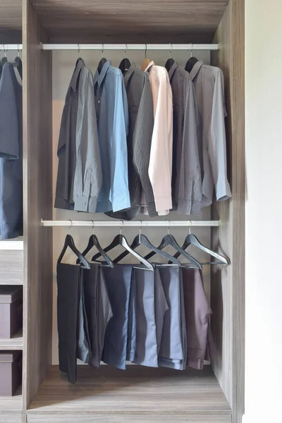Reihe bunter Hemden und Hosen hängen im Holzschrank — Stockfoto