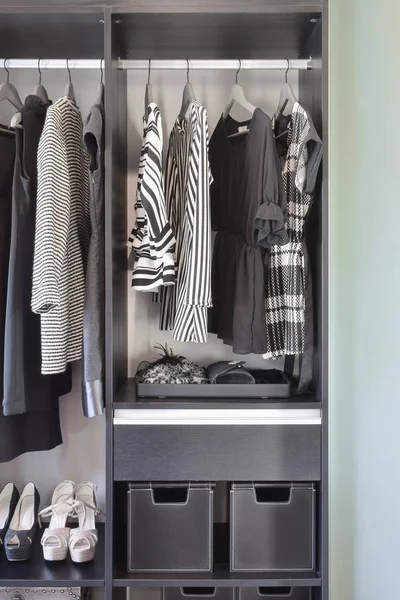 Moderner Kleiderschrank mit einer Reihe schwarzer Kleider und Schuhe im Kleiderschrank. — Stockfoto