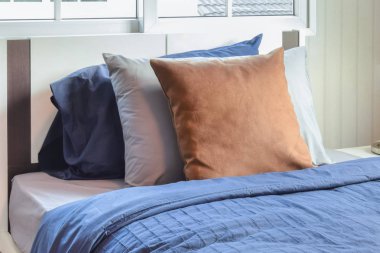 Mavi yatakta kahverengi yastık ile modern yatak odası