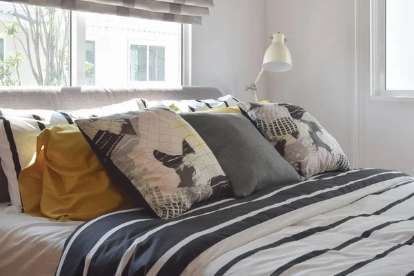 Стильный интерьер спальни с черно-белыми подушками на кровати и декоративной настольной лампой . — стоковое фото