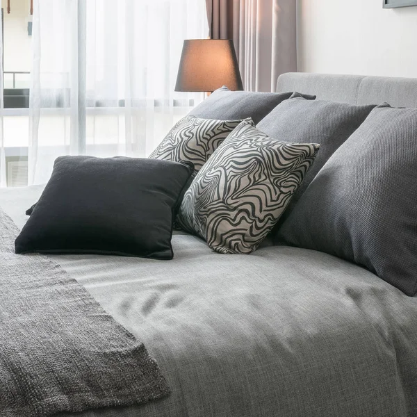 Elegante dormitorio de diseño interior con almohadas con dibujos negros en la cama y lámpara de mesa decorativa . —  Fotos de Stock