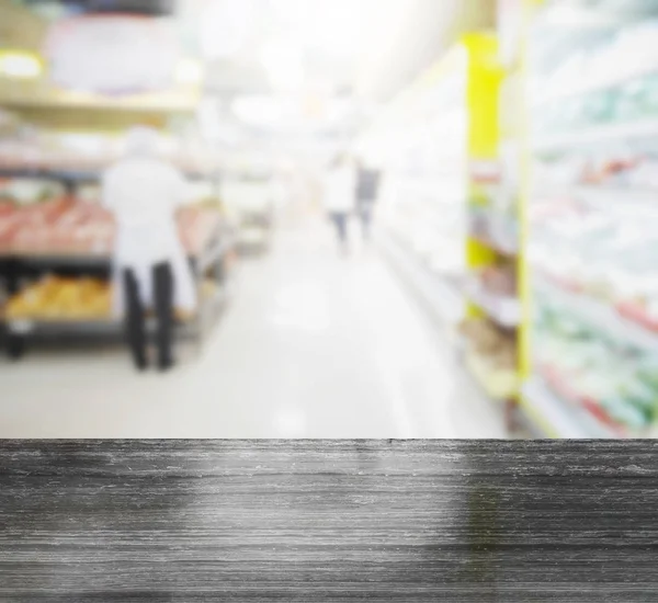 Schwarze Granittischplatte und verschwommene Menschen beim Einkaufen im Supermarkt mit verschiedenen Produkten in den Regalen — Stockfoto