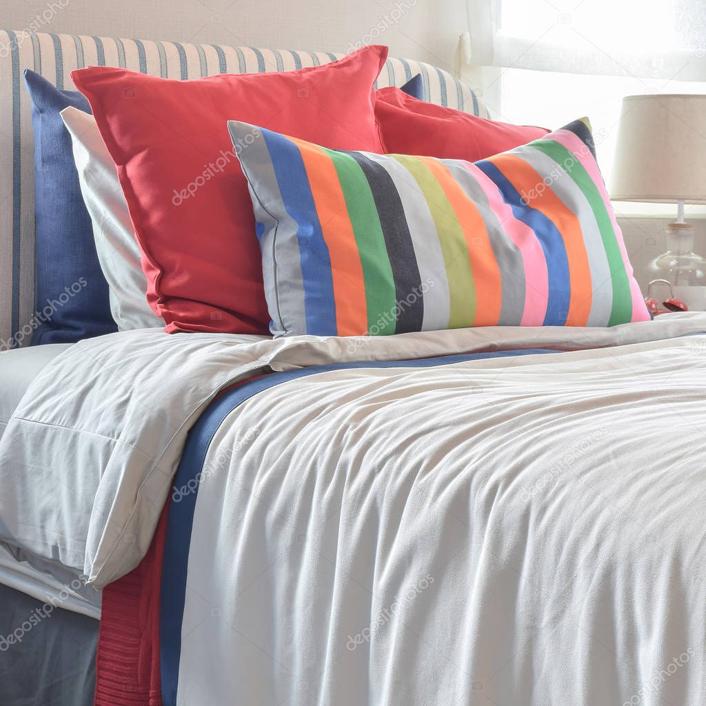 Striped headboard with colorful pillows and striped pillow on white bed sheet