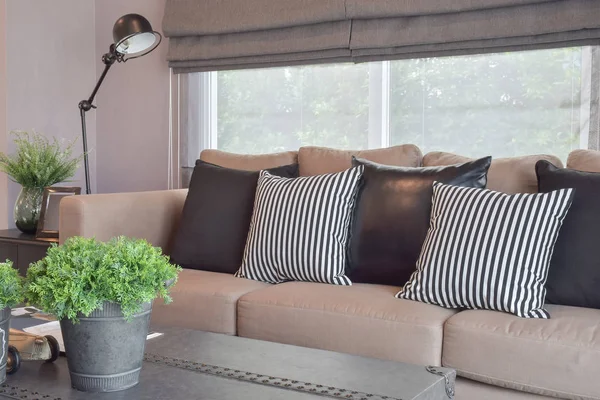 Cosas frescas en la mesa con almohadas de cuero rayas y negras en una sala de estar de estilo industrial moderno — Foto de Stock