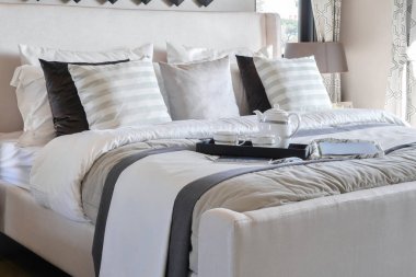 Kitap ve modern yatak odasında yatağın üstünde zarif çay seti ile dekoratif tepsi