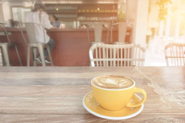 Чашка кави латте на дерев'яному столі в теплих кафетеріях — стокове фото