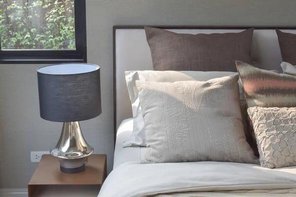 Kissen im eleganten Stil auf Bettwäsche im klassischen Stil und Leselampe auf dem Nachttisch — Stockfoto