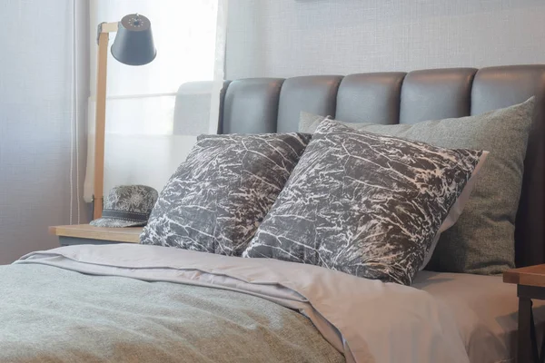 Almohadas de patrón blanco y negro en la cama con cabecero de cuero negro —  Fotos de Stock