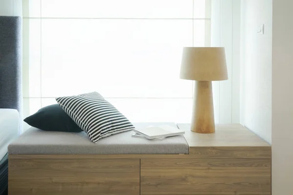 Pillows and reading lamp on cozy seat by the window next to bed — Stock Photo, Image