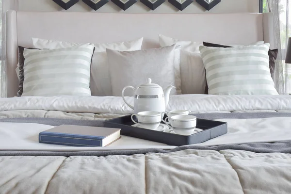 Bandeja decorativa con libro y té en la cama en el dormitorio moderno — Foto de Stock