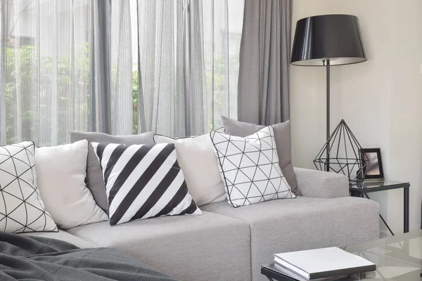 Varierar mönster kuddar i monoton miljö på ljus grå soffa med svart stående lampa — Stockfoto