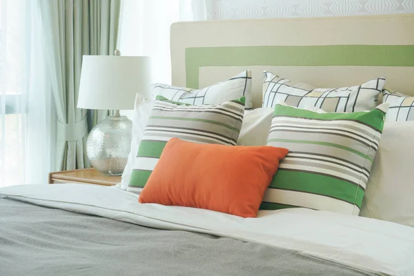 Almohada naranja con almohadas de patrón verde en la cama — Foto de Stock