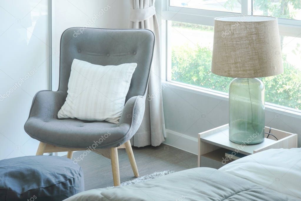 Gray armchair with pillow at the corner of bedroom