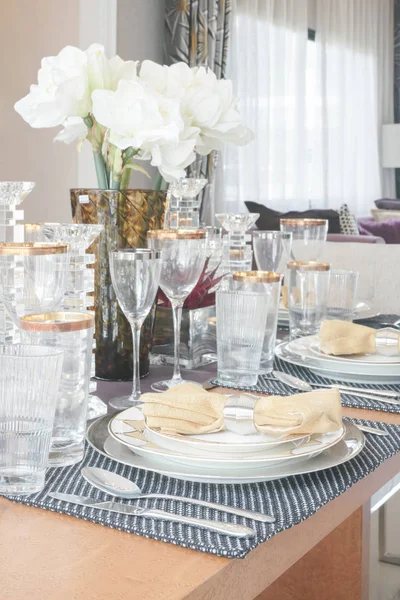 Elegance style dining table with golden trim glassware and white flower in the center of table — Stock Photo, Image