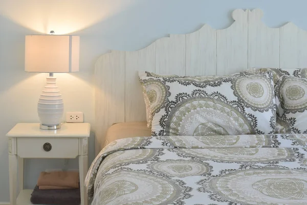 Roupa de cama estilo clássico e lâmpada de leitura com parede azul — Fotografia de Stock