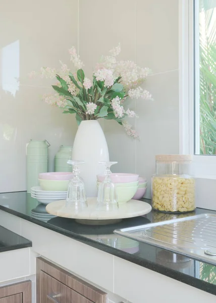Keramik-Geschirr und Blumenvase auf schwarzer Arbeitsplatte in der Küche — Stockfoto
