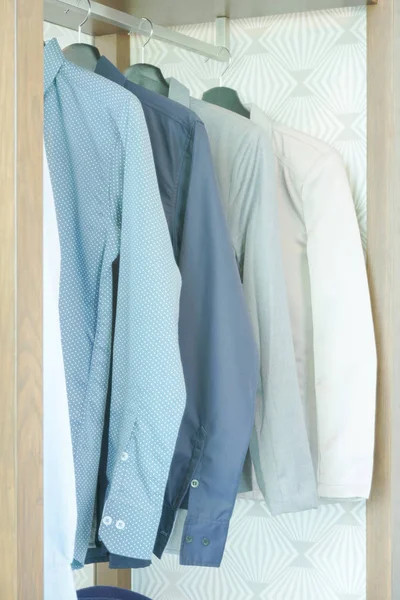 Shirts and men\'s suit hanging in closet