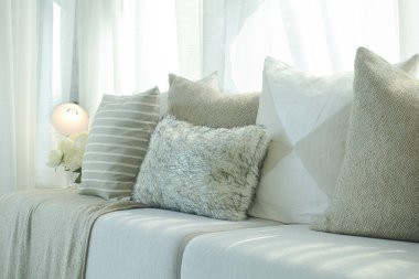 Sıcak oturma odasında doğal ışık ile kahverengi renk düzeni bej kanepe yastık