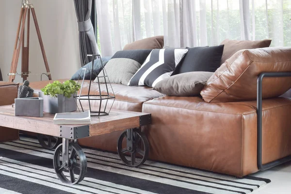Mesa central de madera con rueda y sofá de cuero marrón claro en decoración de estilo industrial — Foto de Stock