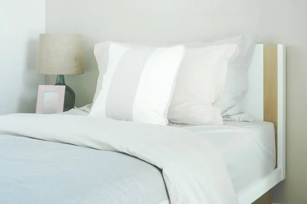 Almohadas de cerca en la cama con lámpara de lectura y marco de imagen —  Fotos de Stock