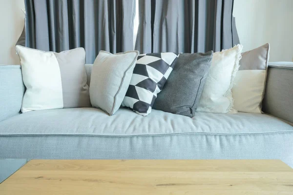 Стильные подушки на сером диване с деревянным столом в гостиной — стоковое фото