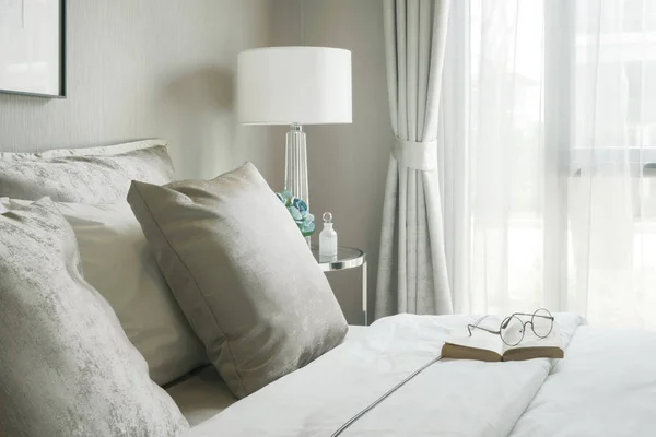 Окуляри і книга про зручне ліжко в сучасній інтер'єрній спальні — стокове фото