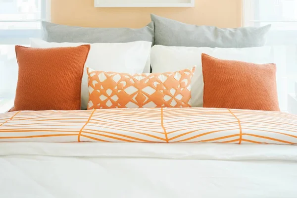 Μοντέρνο υπνοδωμάτιο εσωτερικό με ρολό πορτοκαλί, άσπρο και γκρι μαξιλάρια στο κρεβάτι — Φωτογραφία Αρχείου