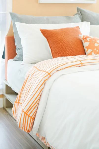 Modern bedroom interior with roll of orange, white and gray pillows on bed — Stock Photo, Image