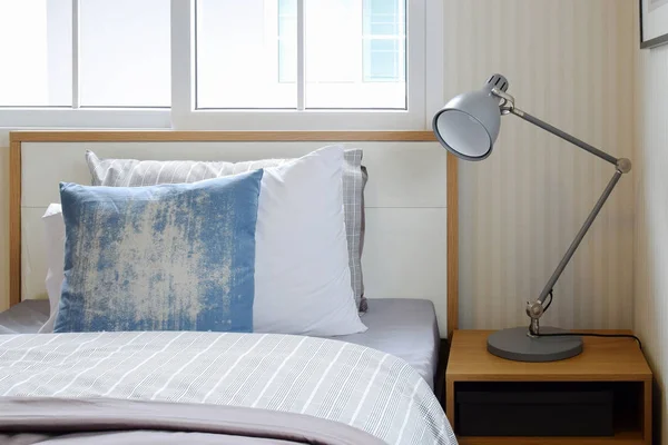 Accogliente camera da letto interna con cuscini e lampada da lettura sul comodino — Foto Stock