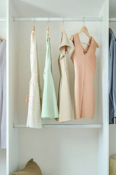 Färgglada kvinnliga kläder hängande i vit garderob — Stockfoto