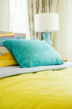 Yatakta sarı battaniye ile yeşil yastık