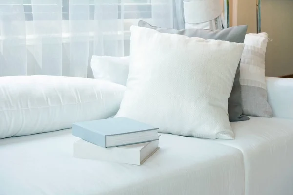 Cuscini bianchi e libri ambientati sul divano bianco nel soggiorno moderno — Foto Stock