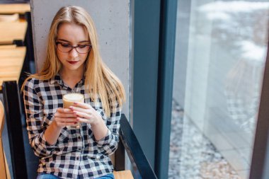 İç ahşap zemin üzerinde oturan ve kahve içme kız