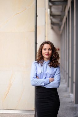 Kameraya dört gözle bina, duvara yakın duran esmer gülümseyen kadın