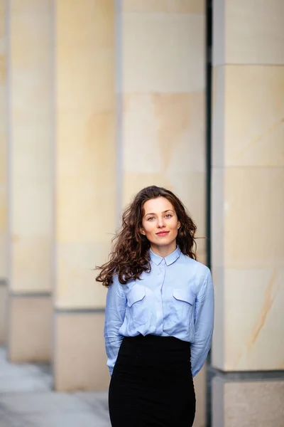 Brunette souriante femme debout près du mur de l'immeuble, impatiente dans la caméra — Photo