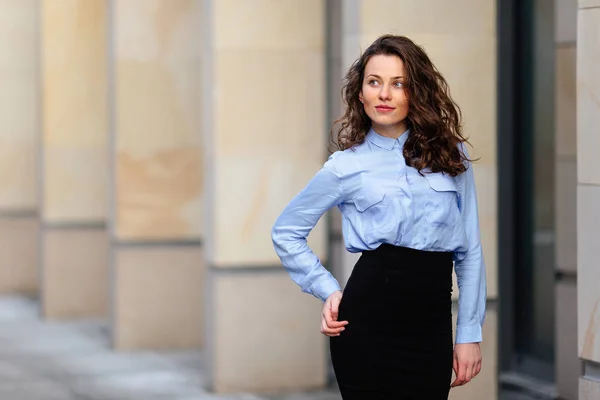 Brunette souriante femme debout près du mur de l'immeuble, impatiente dans la caméra — Photo