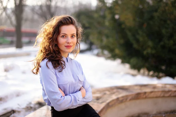 Femme assise sur le banc avec fond de parc et sourire à la came — Photo