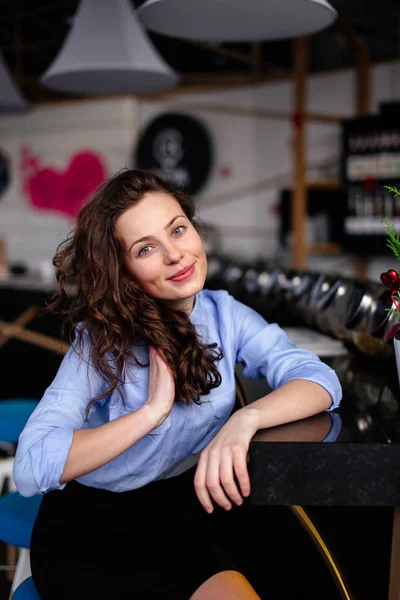 Jolie fille assise près de la table avec une tasse de café et sourire — Photo