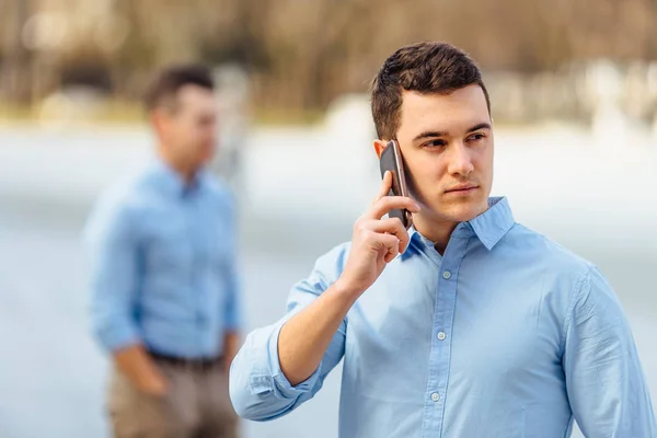 Empresário conversando em seu telefone com amigo no fundo borrão — Fotografia de Stock