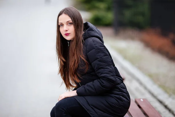Fiatal nő ül a padon, és smilling kamera — Stock Fotó