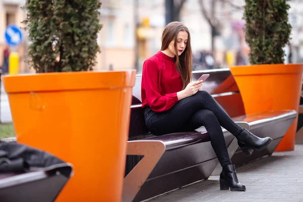 Brunette femme assise dans la rue et textos au téléphone — Photo