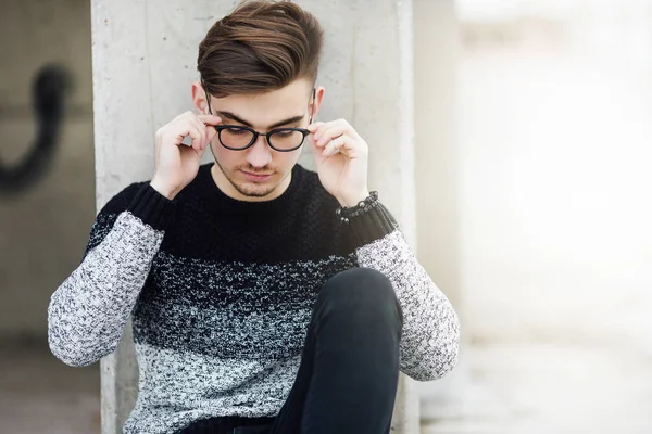 Модний чоловік сидить біля стіни з окулярами на руках — стокове фото