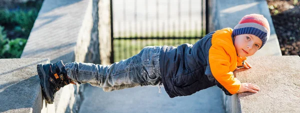 Petit garçon faire pousser des ups à l'extérieur avec fond de soleil — Photo