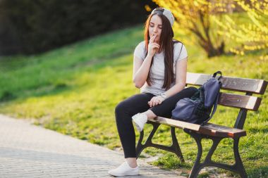 Genç kız duman sigara Park gün batımı ile