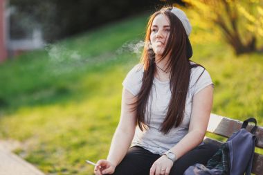 Genç kız duman sigara Park gün batımı ile